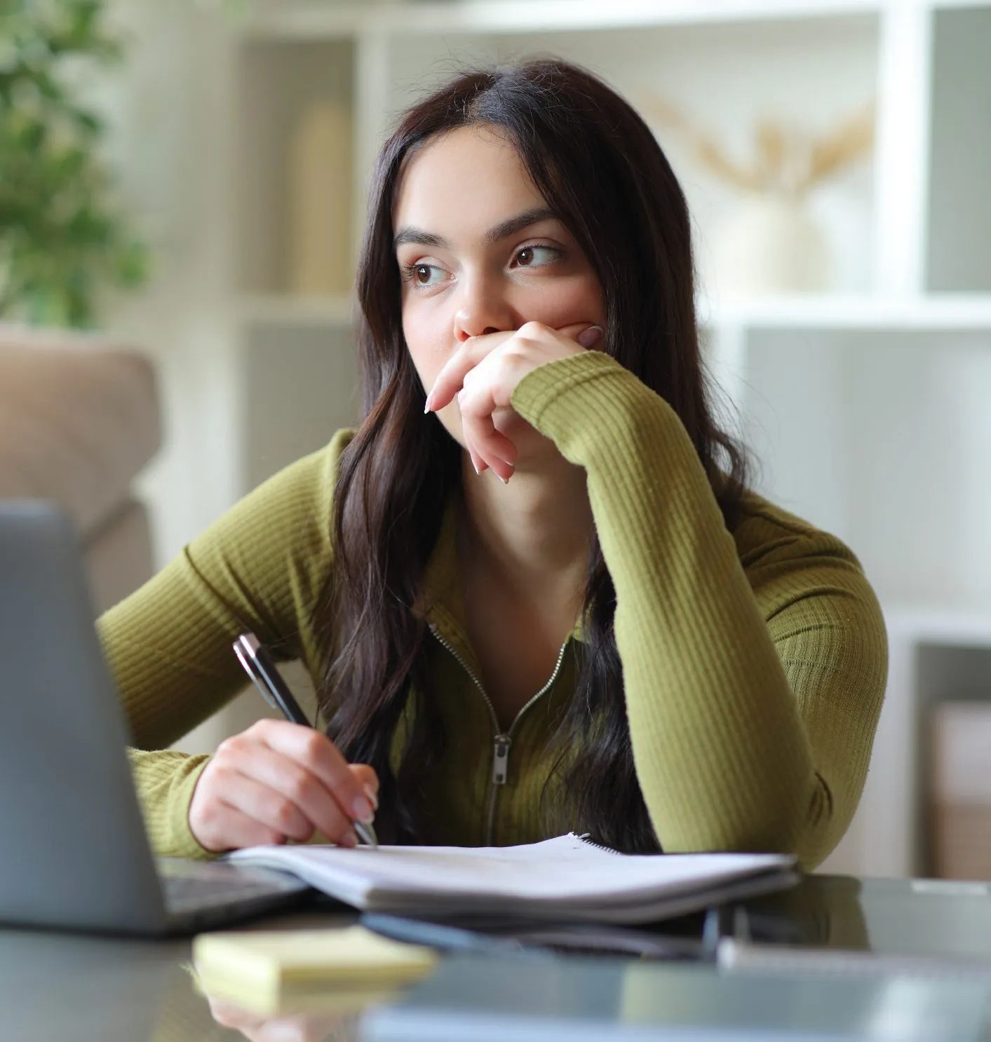 Teenager with her hand over her mouth, distracted while studying