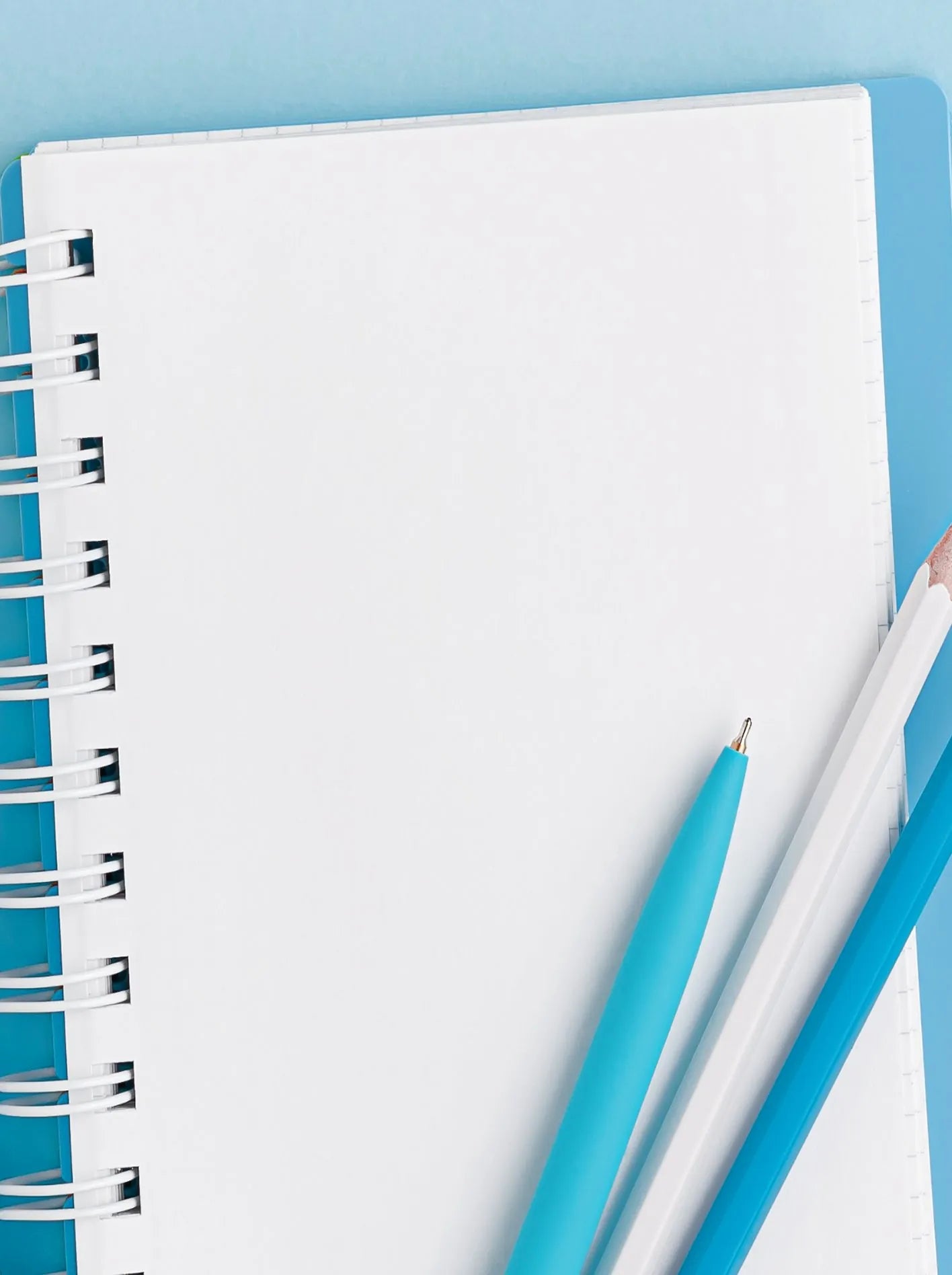 Open spiral notebook with blue pens on a blue desk